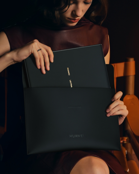 一个女人正在把 HUAWEI MateBook Fold 企业版装进华为折叠电脑尊享收纳包