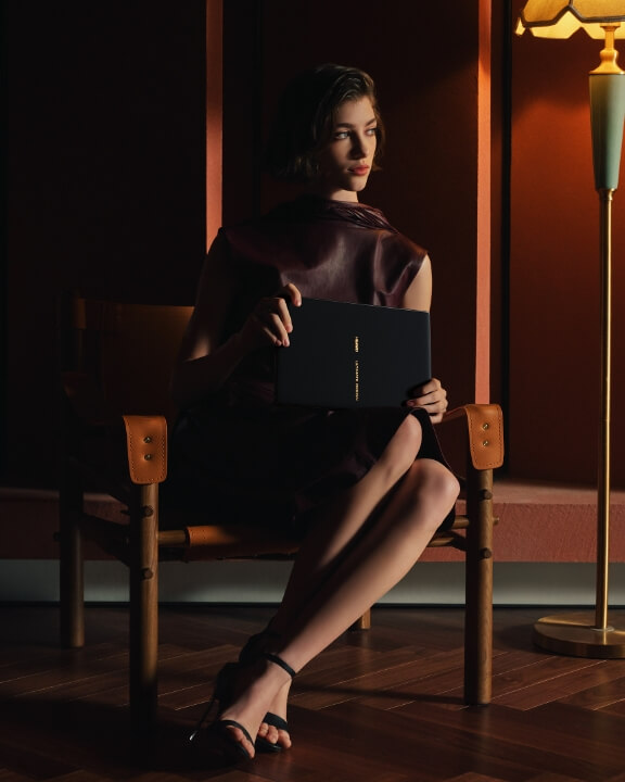 一个女人坐在椅子上，手拿 HUAWEI MateBook Fold 企业版