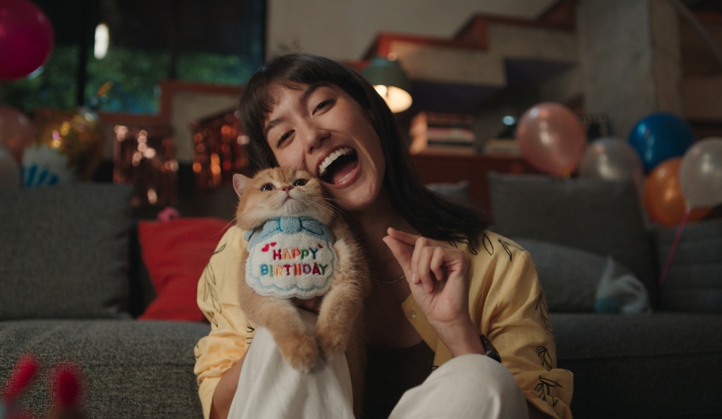 一位佩戴华为擎云 H7556 的女人，抱着她的宠物猫进行合照，通过手势操控隔空完成拍照