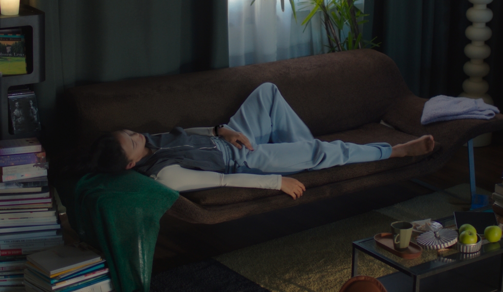 一位佩戴华为擎云 H7556 的女人，在沙发上休息，使用手势操控隔空关闭闹钟