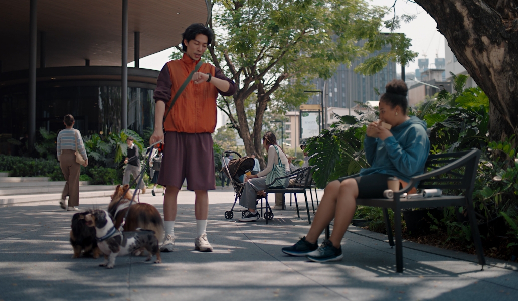 一位男性用户一边遛狗，一边向手腕上佩戴的华为擎云 H7556 发出语音指令